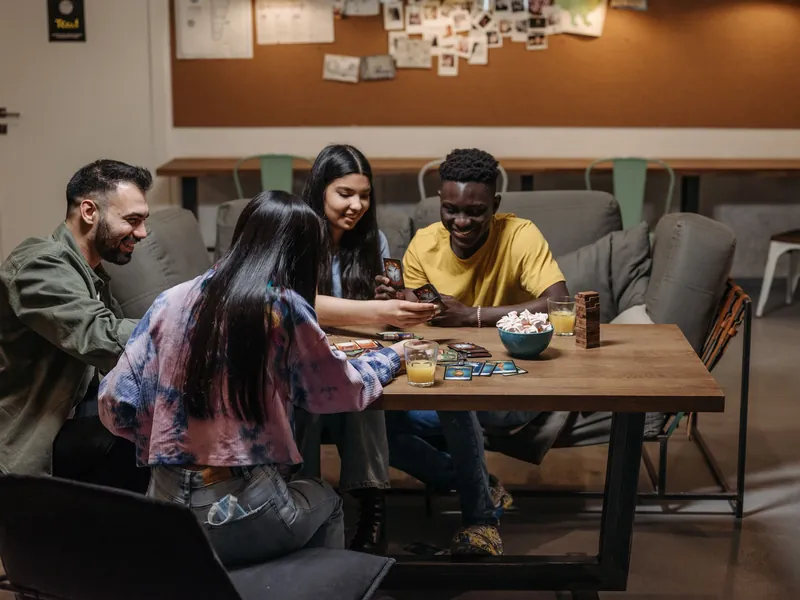Cuatro amigos jugando a las cartas en una mesa, riéndose